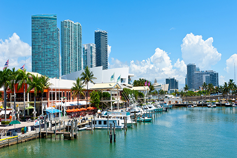 This is a stock photo from Shutterstock. This is a picture of the Shops at Bayside in Downtown Miami. This shopping center sits on the Biscayne Bay. Stores and boats are lined up along the left-hand side of the photo.