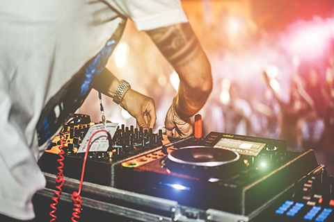 This is a stock photo from Shutterstock. This is an up close image of a DJ adjusting a turntable at a concert.